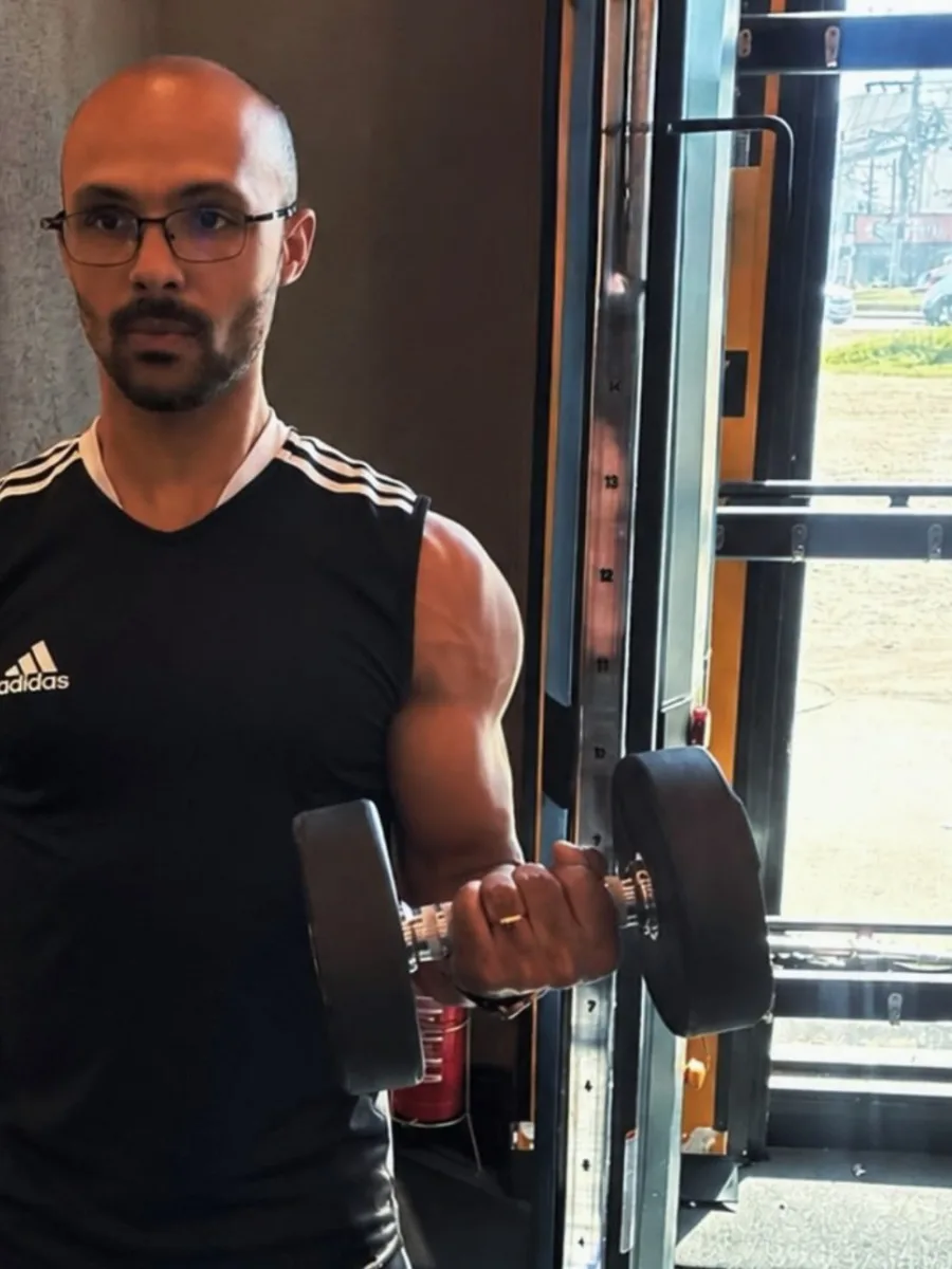 Luiz Gabriel em uma academia, ao lado de equipamentos de musculação.